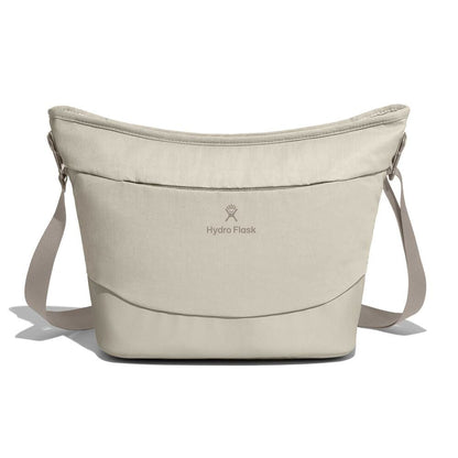 Beige Hydro Flask soft-sided cooler bag with bucket-like curved shape, adjustable straps on both sides, centered logo, and padded durable construction.