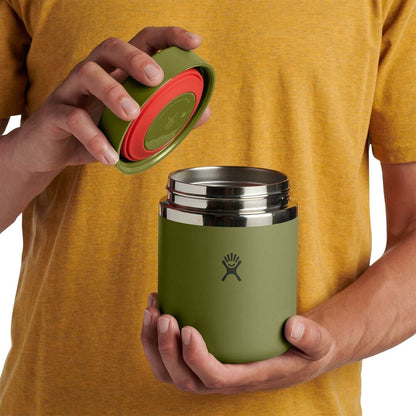 Olive green Hydro Flask insulated container with smooth matte finish, wide cylindrical shape, flat lid, brushed stainless-steel band at top, and logo on front.